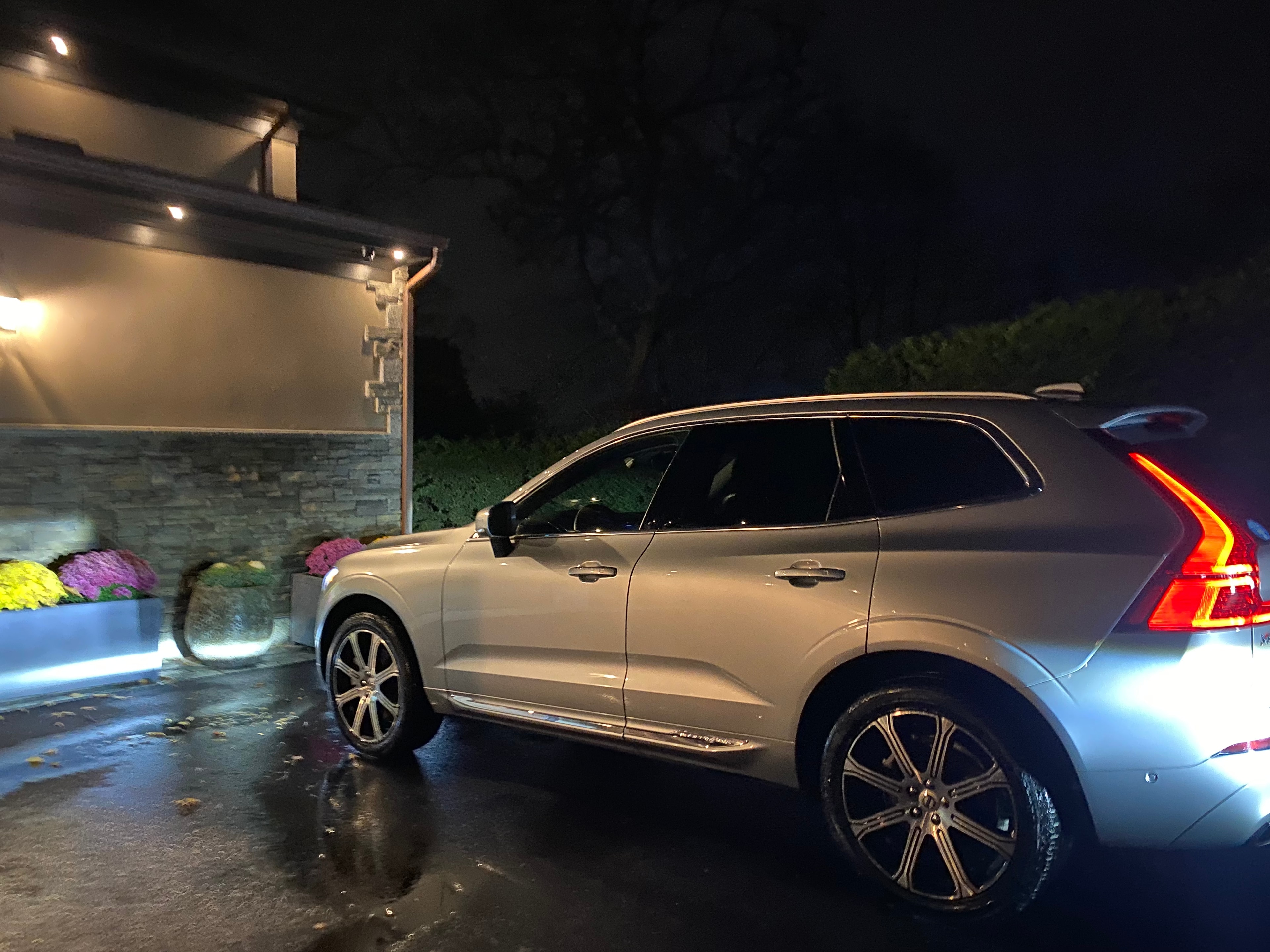 Silver Volvo XC60 gleaming under landscape lighting at night