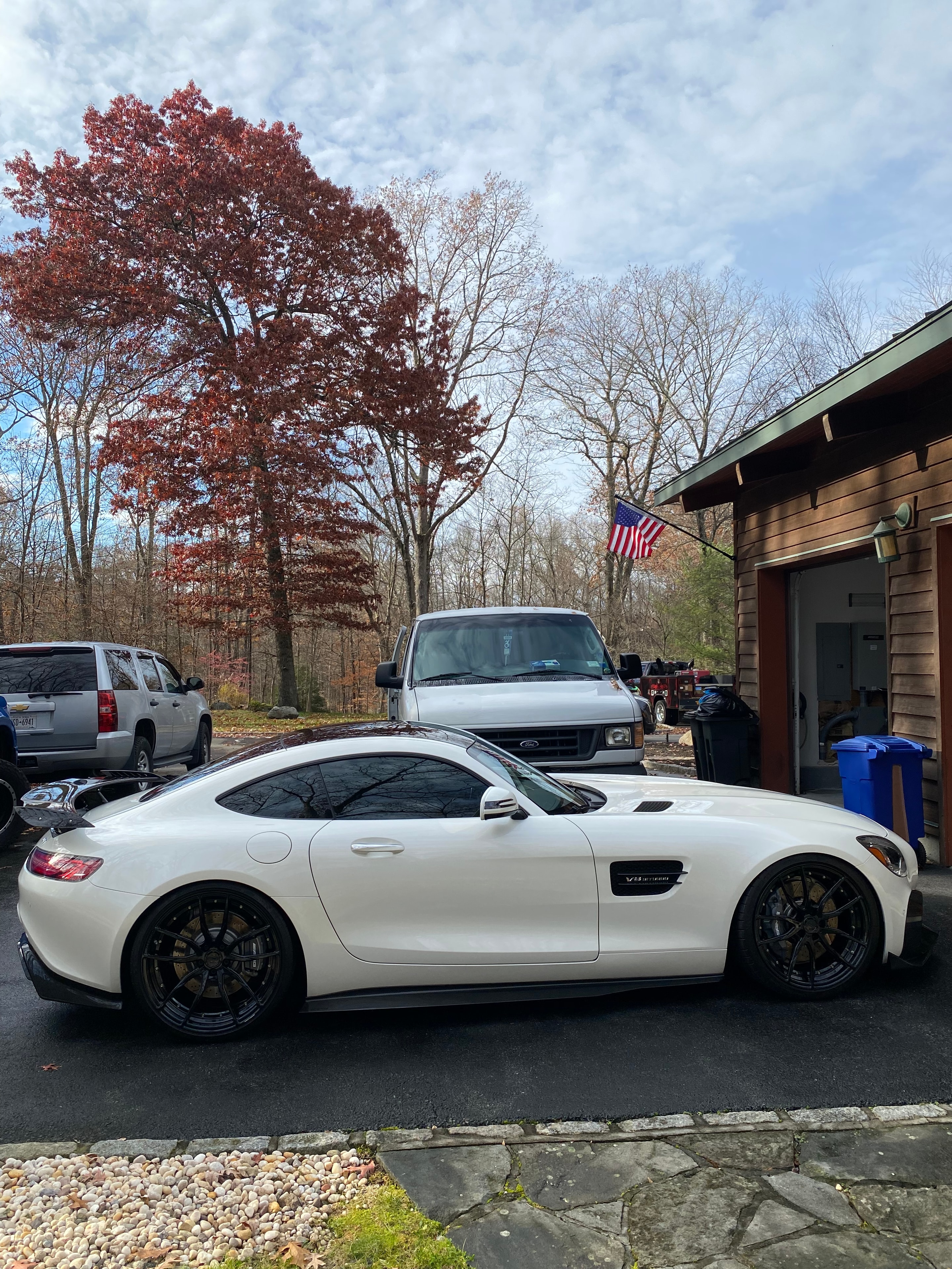 White sports car detailed in a driveway with autumn foliage