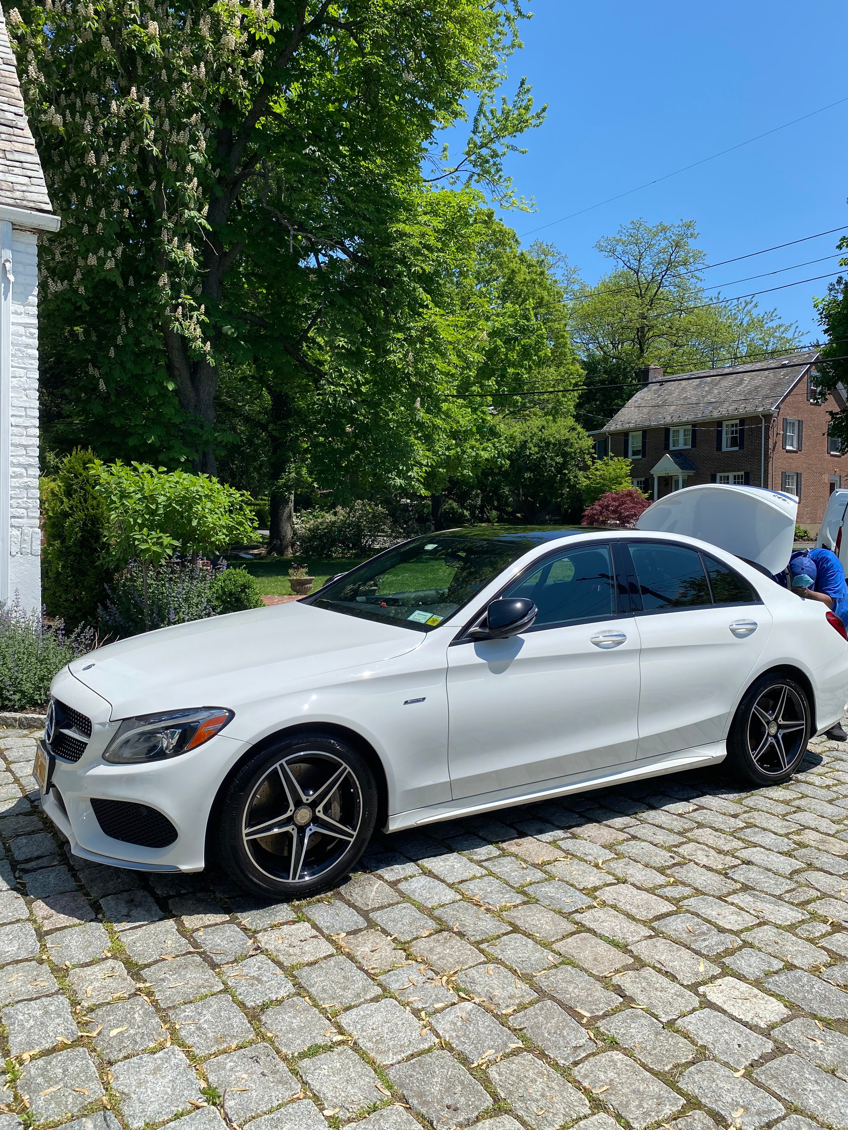 White Mercedes-Benz coupe detailed on a cobblestone street in spring