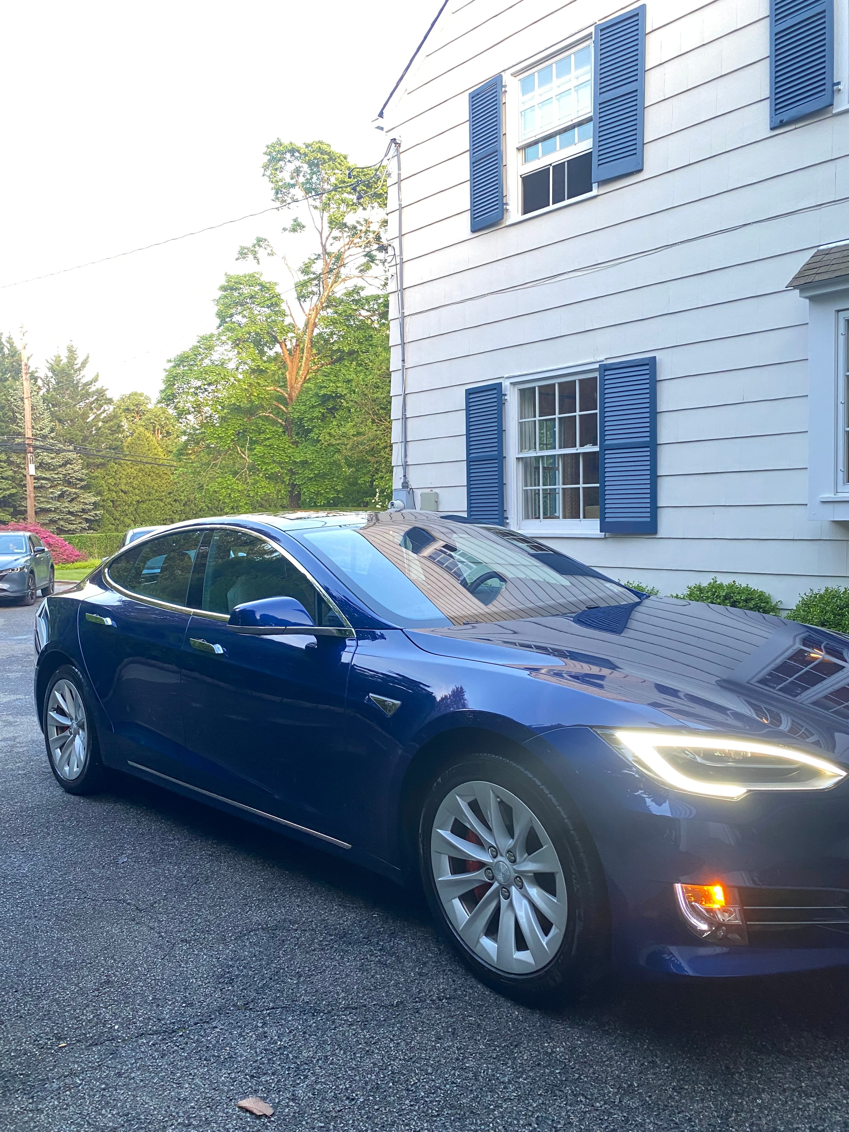 Blue SUV freshly detailed outside a white colonial home at dusk